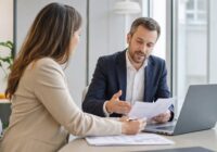 Zwei Personen besprechen in einem modernen österreichischen Büro Gehaltsunterlagen und ein Stellenangebot