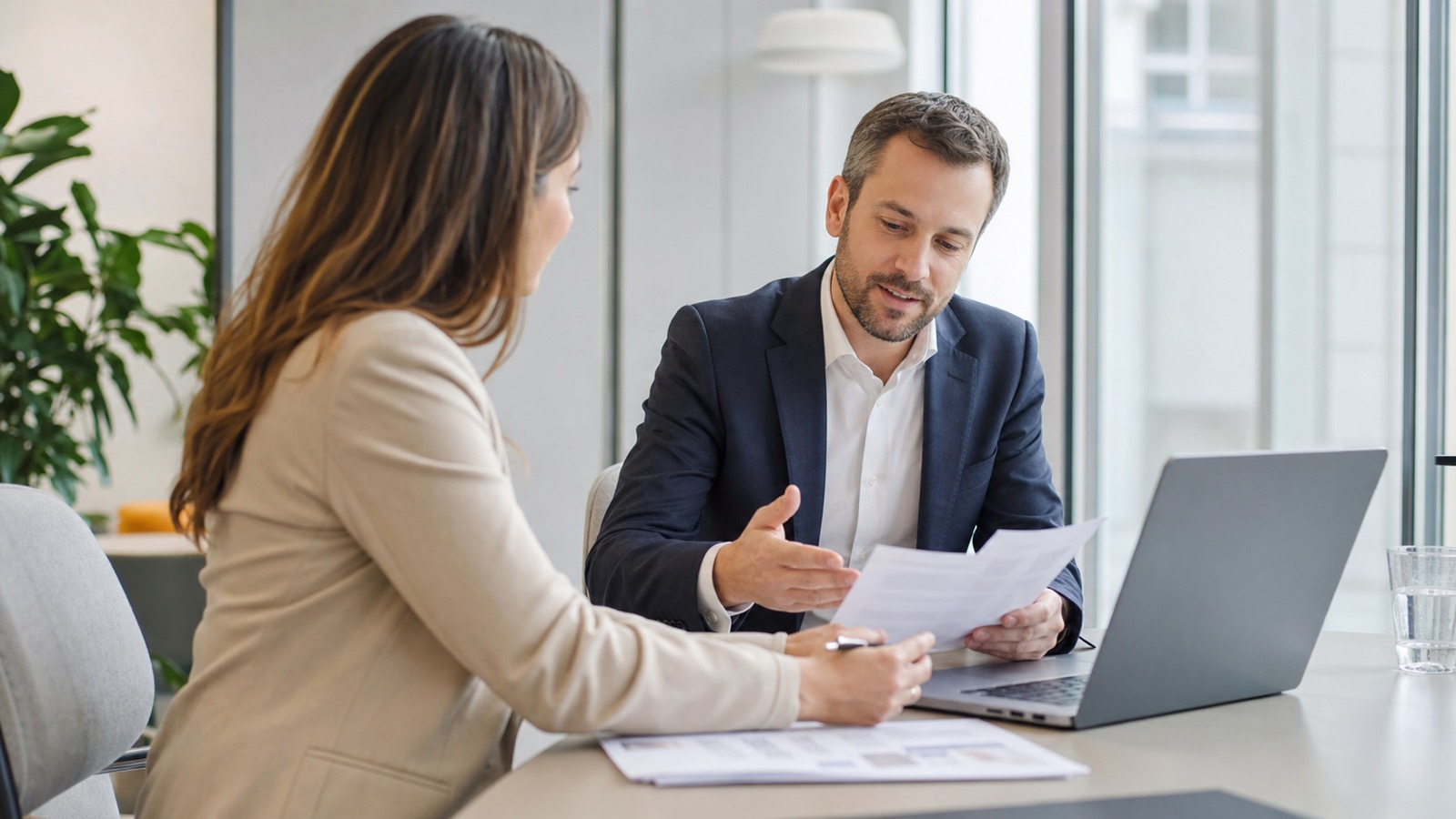 Zwei Personen besprechen in einem modernen österreichischen Büro Gehaltsunterlagen und ein Stellenangebot