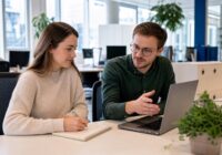 Neue Mitarbeiterin macht sich am ersten Arbeitstag Notizen bei der Einarbeitung in einem modernen österreichischen Büro