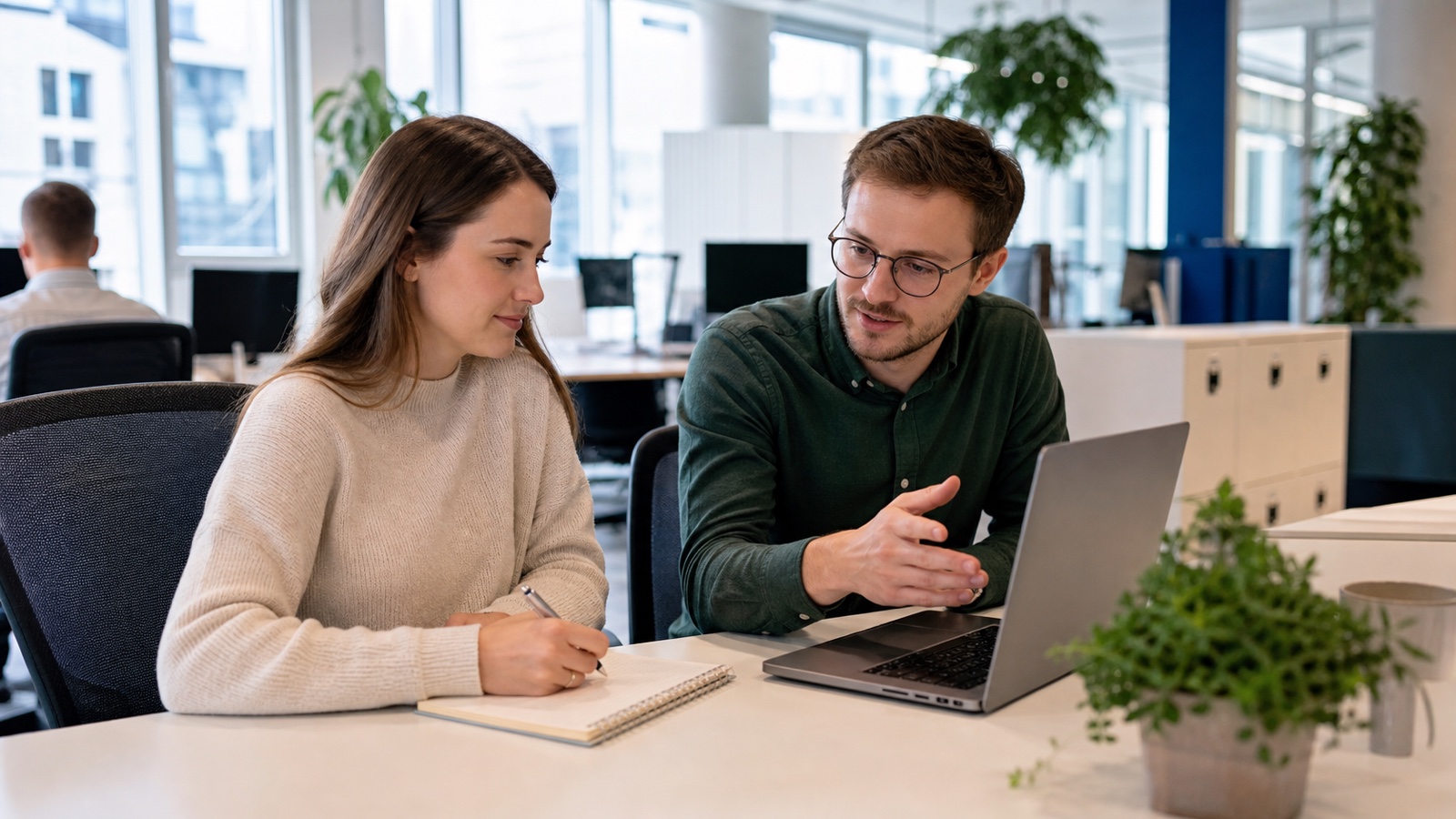 Neue Mitarbeiterin macht sich am ersten Arbeitstag Notizen bei der Einarbeitung in einem modernen österreichischen Büro