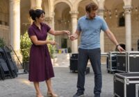 Zwei erwachsene Beschäftigte übergeben in einem sommerlichen Wiener Kulturhof Aufgaben und Schlüssel für eine Urlaubsvertretung