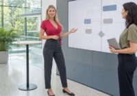 Blonde erwachsene Bewerberin erklärt in einem sommerlichen österreichischen Vorstellungsgespräch ihre praktische KI-Kompetenz