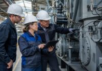 Adult maintenance technicians in an Austrian workshop jointly inspect a machine and its maintenance data