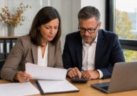 Adult payroll clerks in an Austrian office jointly examine a payroll statement and a checklist